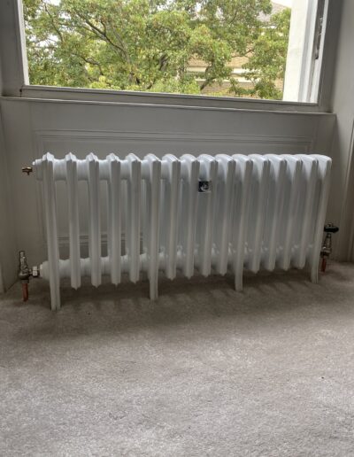 White cast iron column radiator fitted under a window in a period property