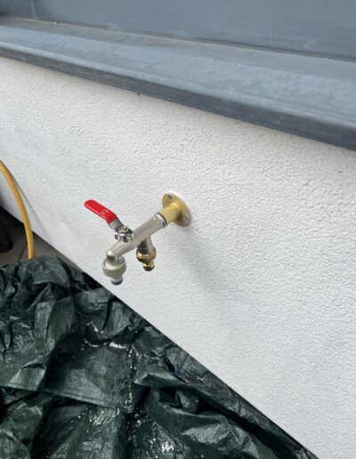 Outside garden bib tap with isolation valve installed on a rendered wall