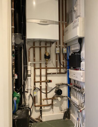 Vaillant boiler in an airing cupboard with copper pipework and underfloor heating manifold