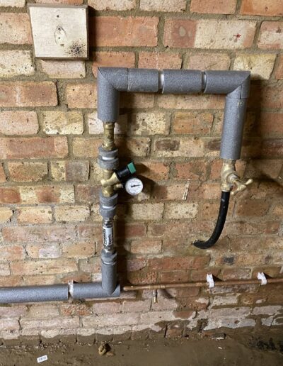 New water main with stopcock and pressure reducing valve on exposed brickwork